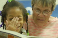 girl reacts in laughter over book with volunteer
