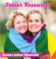 two smiling women wrapped in a rainbow flag