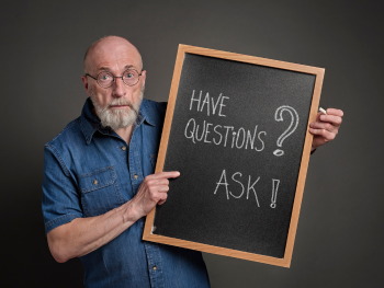 man holding sign that says "Have questions? Ask!"