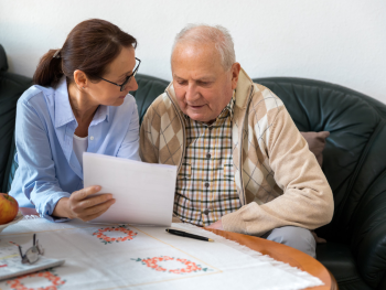 caregiver reads page with older man