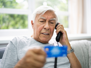 man talking on phone and holding a credit card