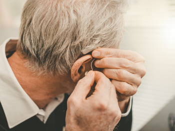 man puts on hearing aid