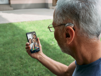 man with hearing aid uses mobile phone