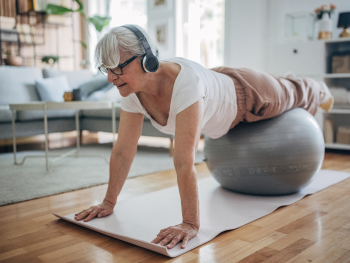 older woman uses exercise ball in her living room