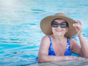 mature woman in a pool with sunglasses and a sun hat