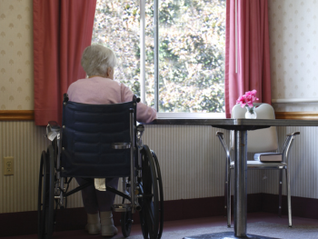 older woman in wheelchair looking through a window