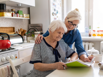 older woman and her daughter look at documents in the kitchen