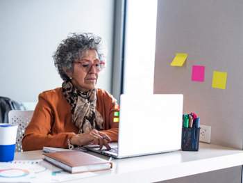 woman with curly grey hair works at computer