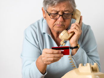 older man holds phone and looks at credit card