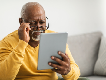 man adjusts glasses to look at a tablet