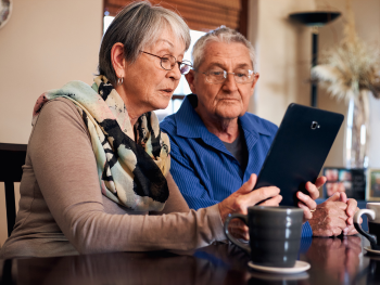 two older adults looking at a tablet